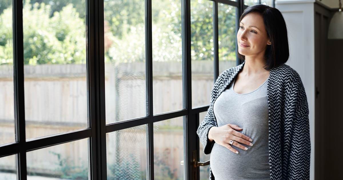 Pregnant woman stares out window. Pregnant woman stares out window.